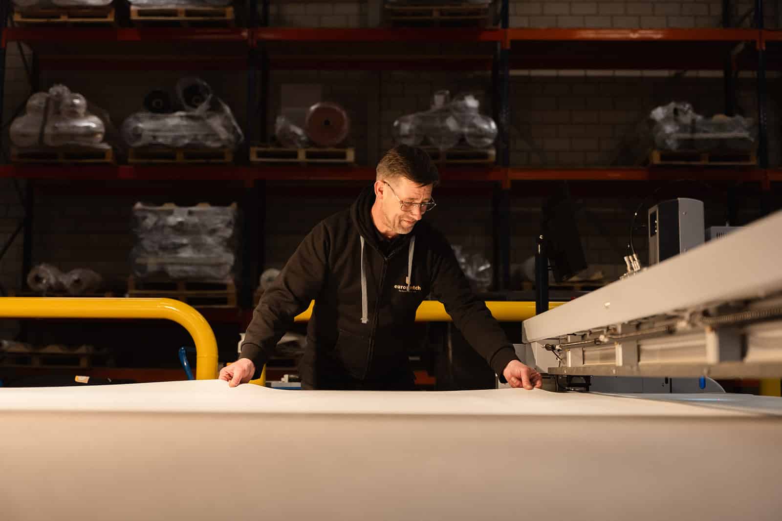 Jos legt de stretchstof goed om gesneden te worden door de snijmachine